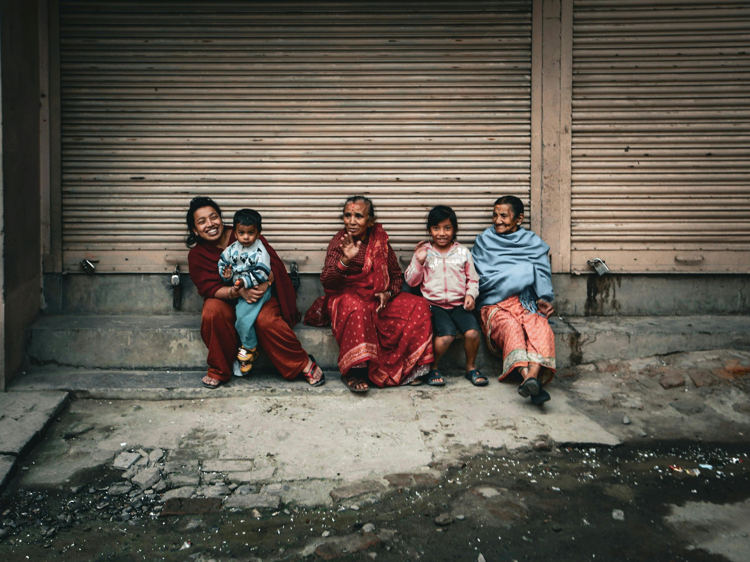 Family of different ages smiling together on an urban sidewalk.